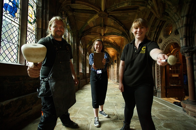 Three heritage professionals within the cathedral holding historical items